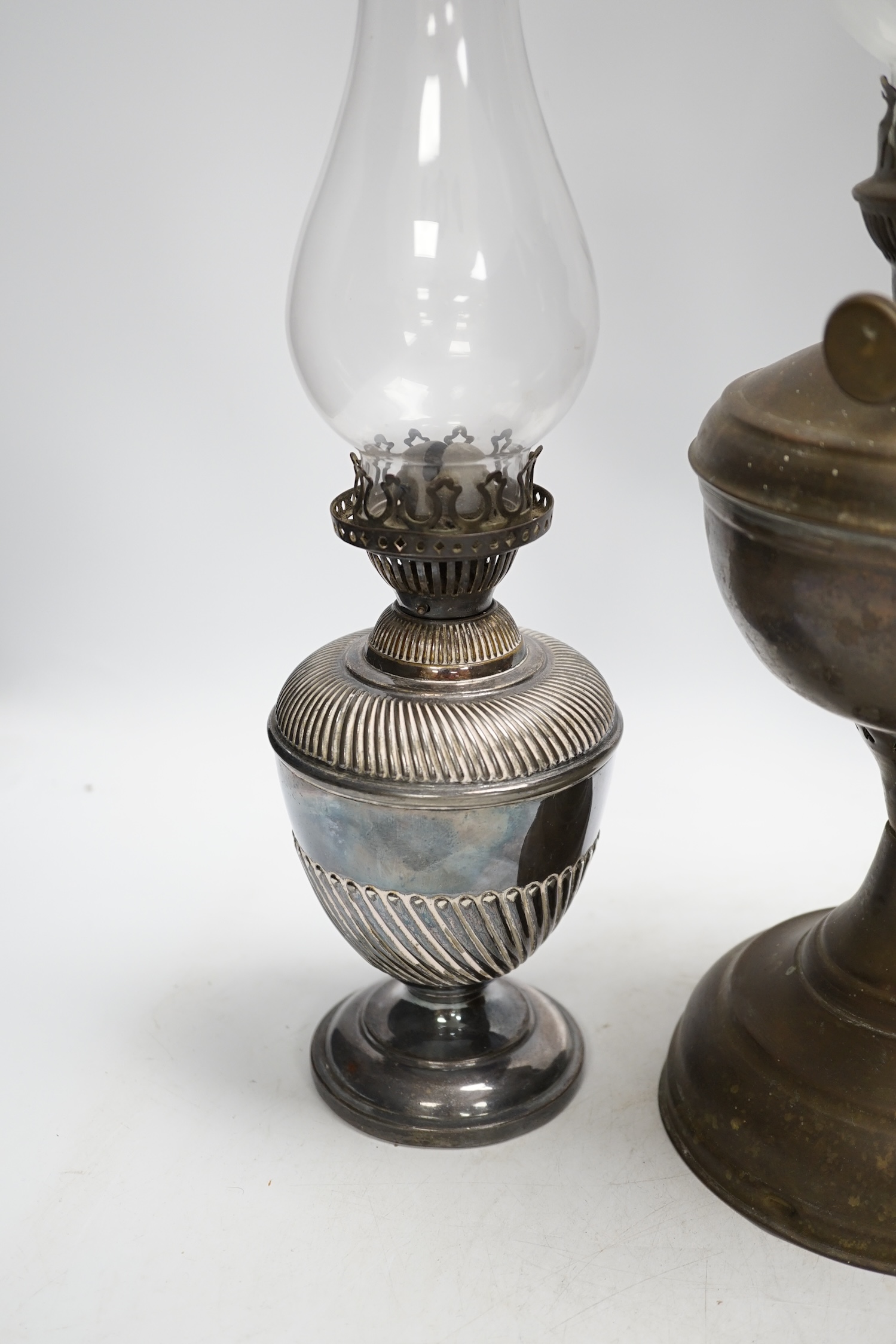 A brass oil lamp and a smaller pair of silver plated oil lamps with glass funnels, tallest including funnel 54cm high. Condition - fair